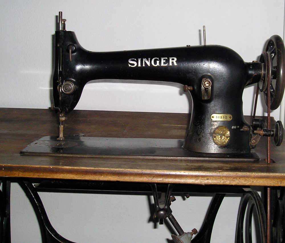 An old black Singer sewing machine sits on a wooden table