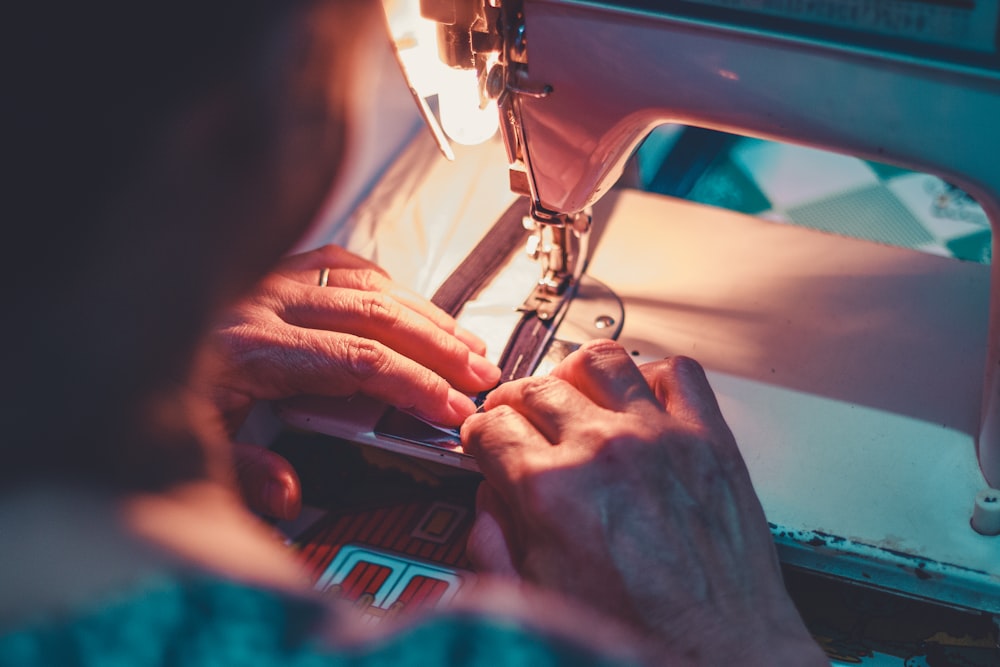 A person's hands guide fabric under the needle of a sewing machine