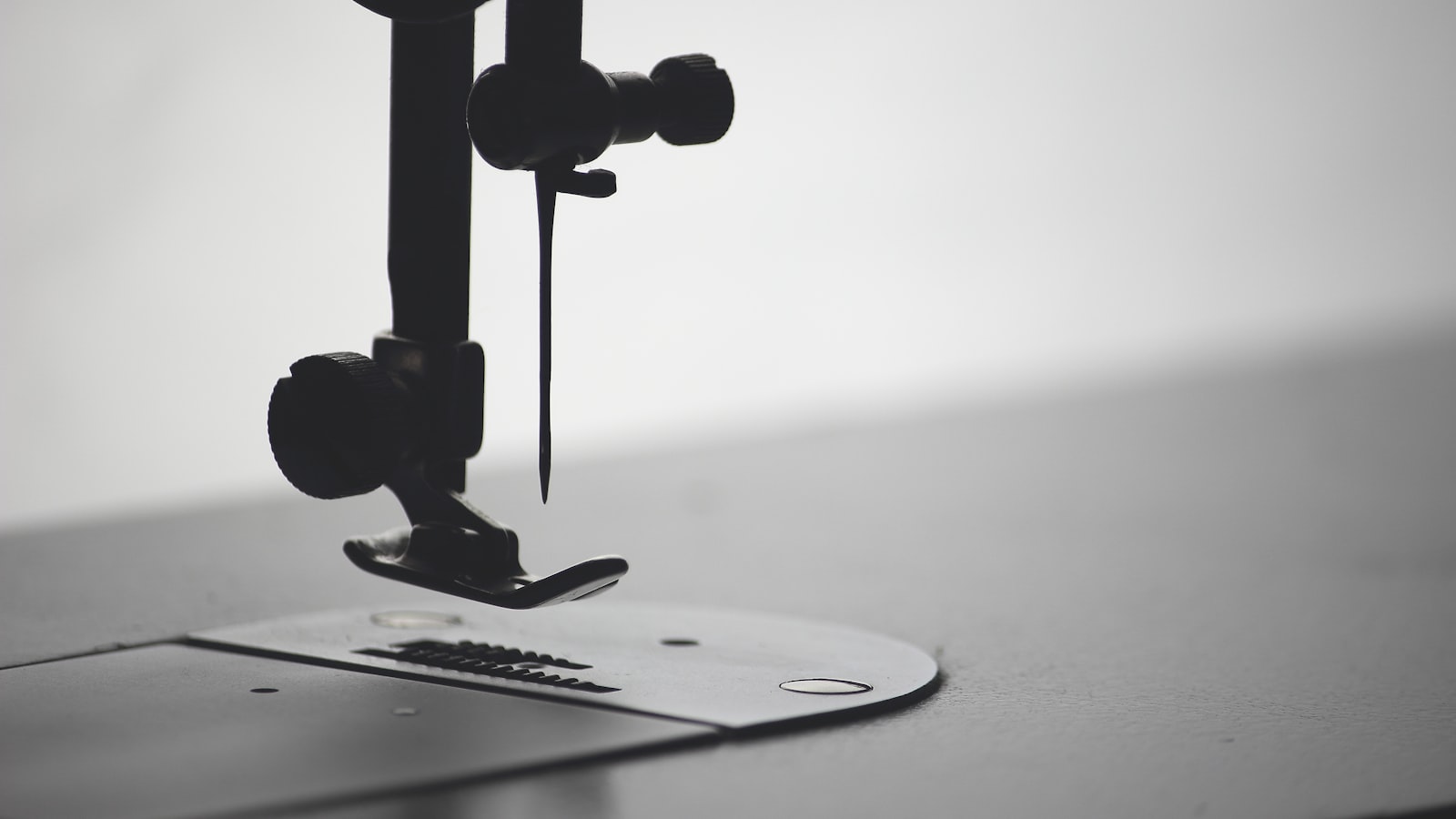 Black and white close-up of a sewing machine presser foot and needle