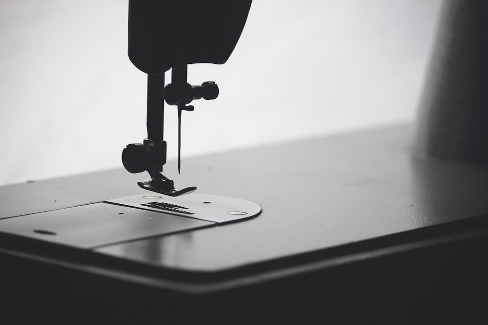 A close-up black and white photo of a sewing machine needle and presser foot