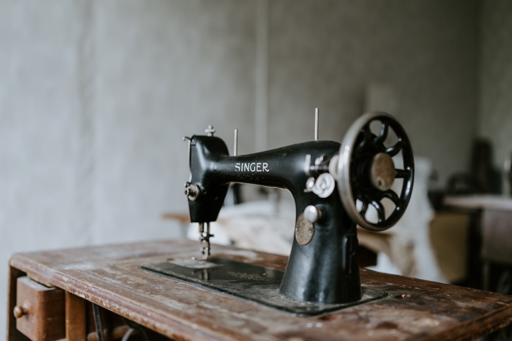 An antique black sewing machine sits on a weathered wooden table
