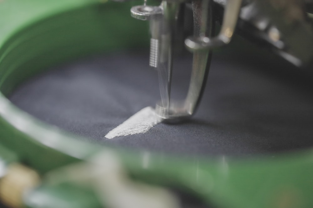 Close-up of a sewing machine needle stitching white thread onto dark fabric