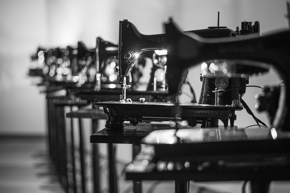 A long row of vintage sewing machines extends into the background in black and white