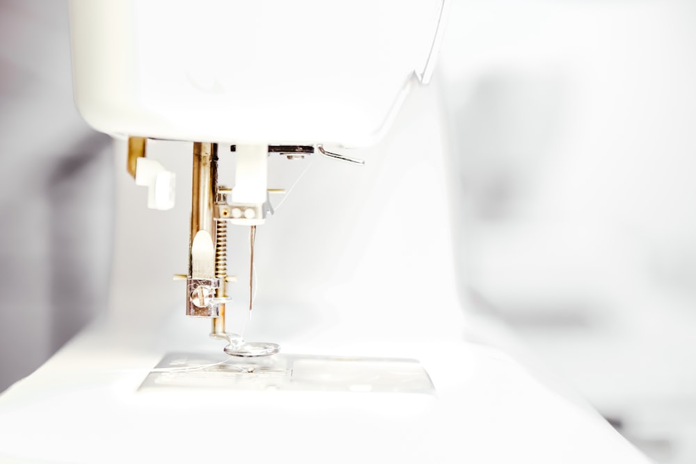 Close-up of the needle and presser foot of a white sewing machine