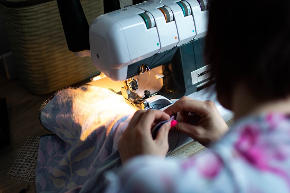 A person feeds patterned fabric into a white serger sewing machine
