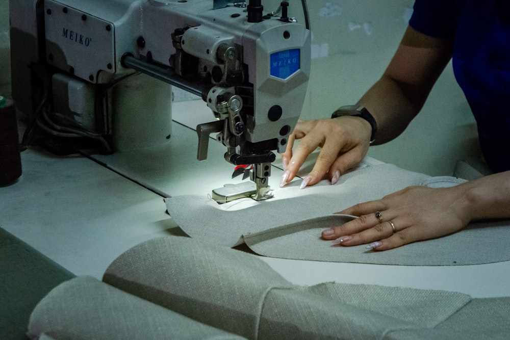 A person guides fabric under the needle of an industrial sewing machine
